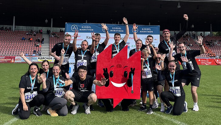 Gruppenbild von Team fabrikon mit Maskottchen fabrikonchen auf dem Kassel Marathon 2025 Gruppenbild von Team fabrikon mit Maskottchen fabrikonchen auf dem Kassel Marathon 2025